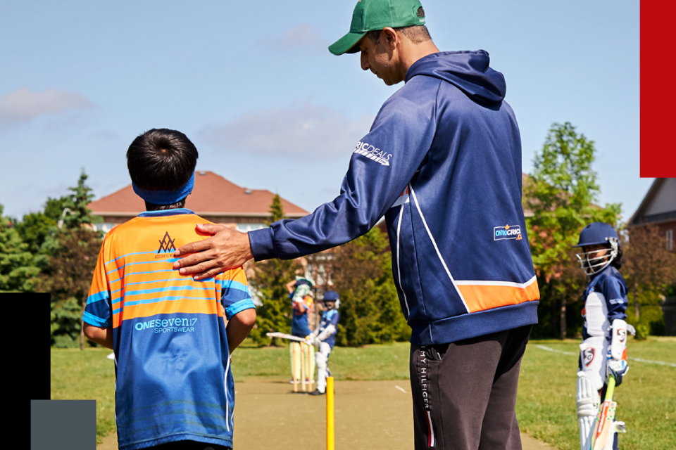 Cricket coach supporting young athlete.
